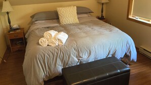 A bedroom with a bed, two bedside tables, a window, and a bench.