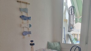 Et rundt bord med dug med stjerneform, fire blå stole, en hængende makramédekoration, og udsigt til en balkon med stol og makraméstol.