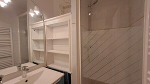 A bathroom with a sink, mirror, and shower enclosure.