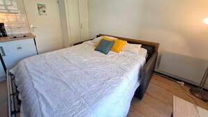A single bed with a wooden headboard, a bedside table, and a small desk with a chair.
