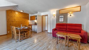 A compact living space with a dining area, kitchenette, and a red sofa. - 40m from ski slopes, 3rd floor, view mountain, fitness, swimming pool, sauna, balcony, tv (Les Orres)