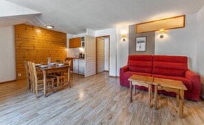 A compact living space with a dining area, kitchenette, and a red sofa. - Resort center, 3rd floor, view mountain, fitness, swimming pool, sauna, balcony, tv, ski locker (Les Orres)