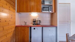 A compact kitchen with wooden cabinets, a microwave, a coffee maker, and a dishwasher. - 40m from ski slopes, 3rd floor, view mountain, fitness, swimming pool, sauna, balcony, tv (Les Orres)