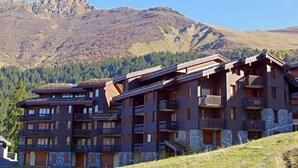 Een hotel met meerdere verdiepingen en balkons, gelegen voor een bergachtig landschap.