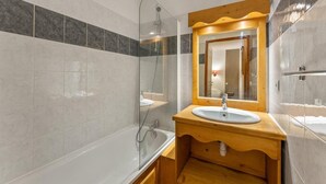 Une salle de bain moderne avec une douche à parois de verre, un meuble-lavabo en bois et un grand miroir.