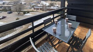 A balcony with a table and chairs, overlooking a snowy landscape and a parking area. - 5th floor, balcony, tv, 43m², Villard de Lans (Villard-de-Lans)