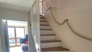 A staircase with wooden steps and white walls, leading to a room with a large window and a view of the outdoors. - 5th floor, balcony, tv, 43m², Villard de Lans (Villard-de-Lans)
