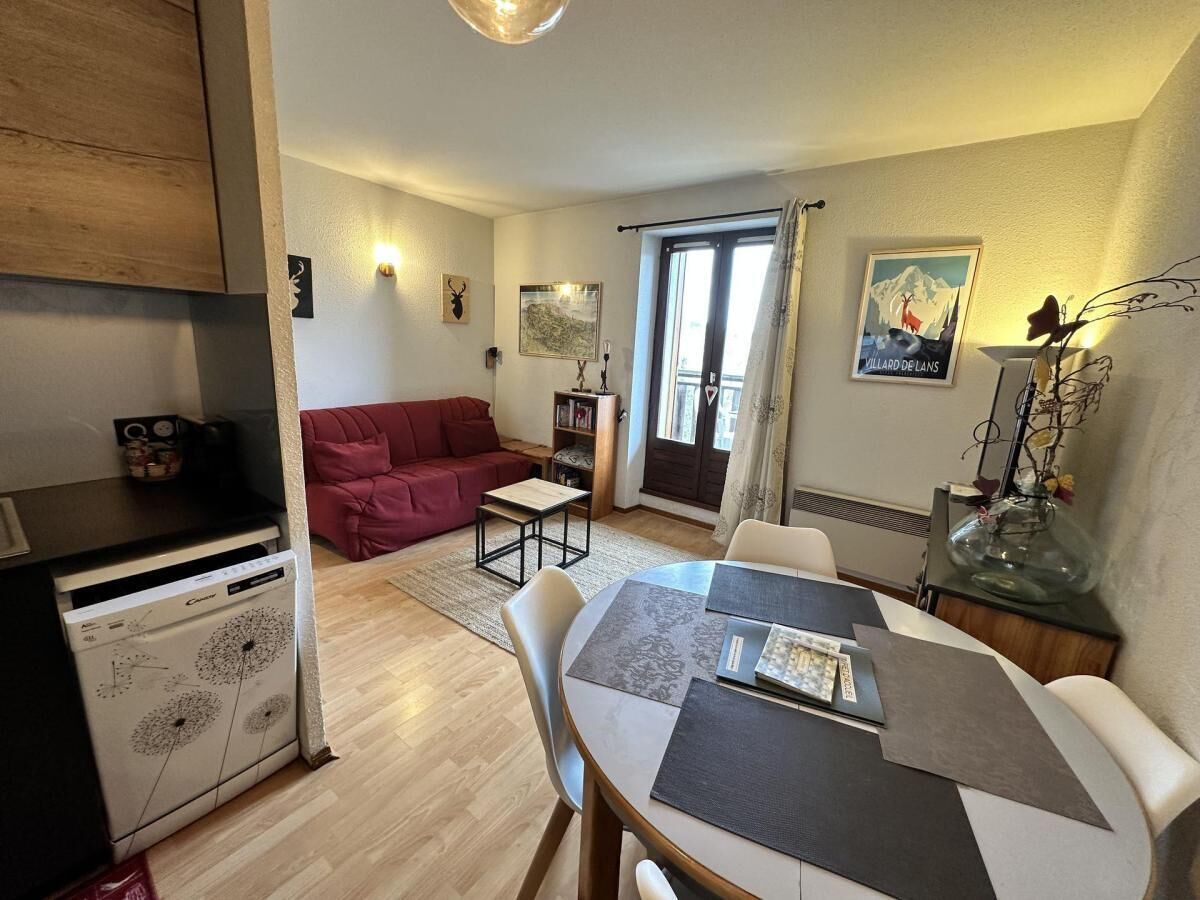 A compact living space with a kitchenette, a dining area, and a red sofa.
