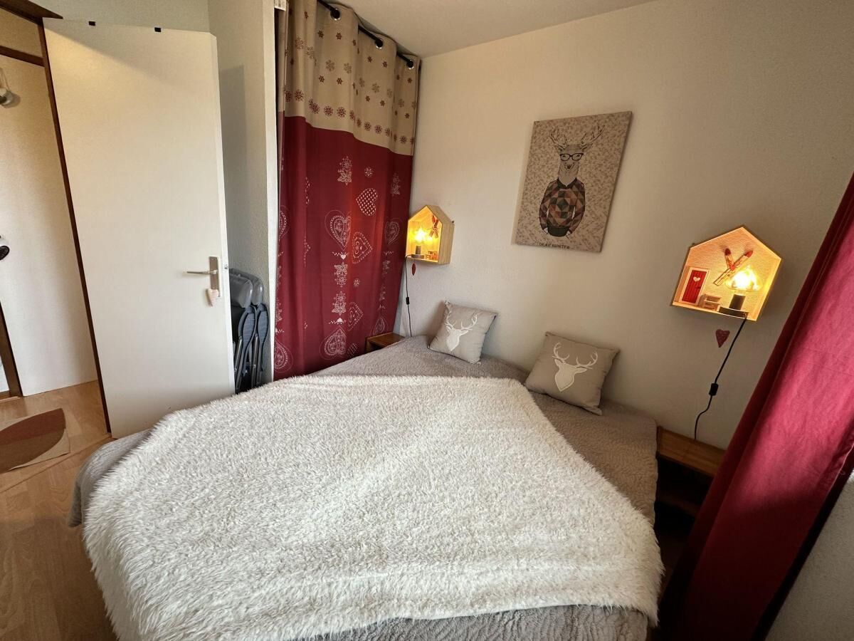 Een slaapkamer met een groot, zacht bed, een houten deur, een rood gordijn en twee wandlampen.