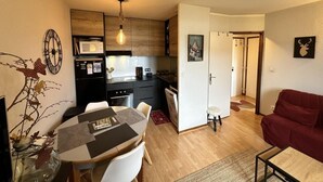 Un espacio habitable compacto con comedor, kitchenette y un sofá rojo.