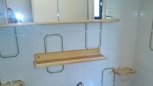 A bathroom with a white sink, wooden cabinets, and a mirror above the sink.