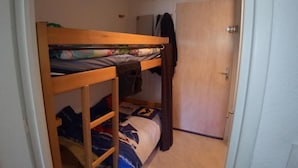 A bunk bed with a lower bunk and a door to a closet.
