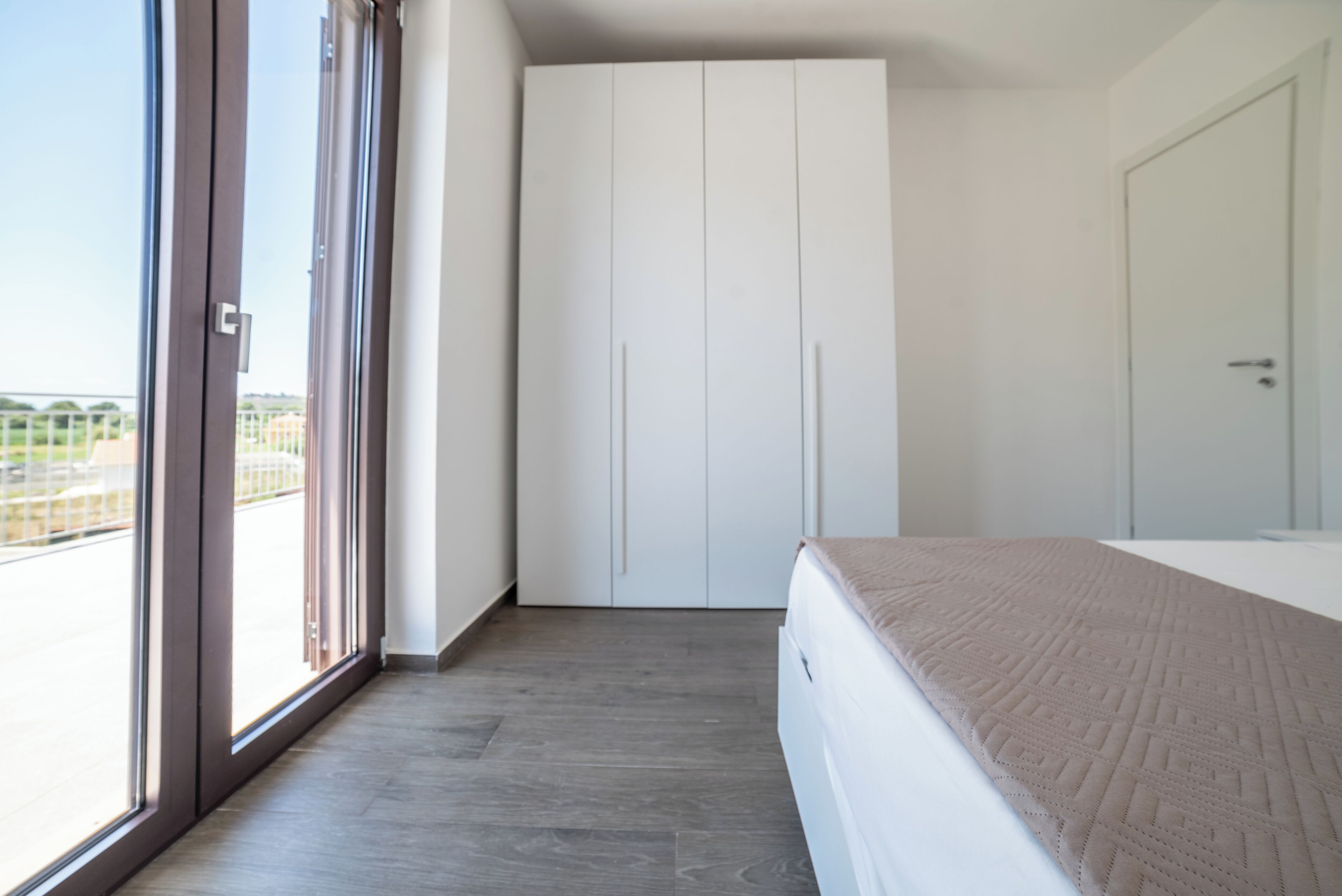 Una camera da letto con un letto, un armadio e una porta scorrevole in vetro che dà sull'esterno.