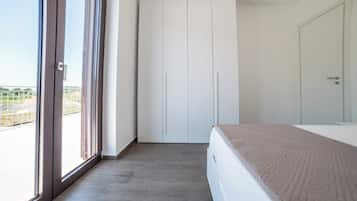 Una camera da letto con un letto, un armadio e una porta scorrevole in vetro che dà sull'esterno.