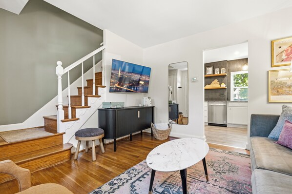 A modern living room with a staircase, a dining area, and a kitchen.