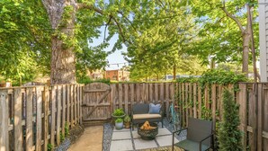 Ein Garten mit einer Holzterrasse, einer Bank, einem kleinen Tisch und einem Blumentopf.