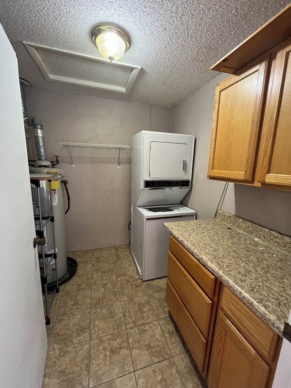 Una cocina compacta con refrigerador integrado, pileta y alacenas de madera.