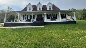 A large, two-story house with a covered porch, a front staircase, and a small play area with a slide. - Family friendly 12 bed, Serene small town Louisa. Cozy with wifi, AC & farm life (Louisa)