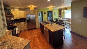 A kitchen with granite countertops, stainless steel appliances, and wooden flooring. - Family friendly 12 bed, Serene small town Louisa. Cozy with wifi, AC & farm life (Louisa)