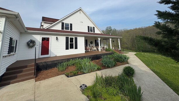 A white two-story house with a red door, a covered porch, and a landscaped front yard. - Family friendly 12 bed, Serene small town Louisa. Cozy with wifi, AC & farm life (Louisa)