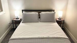Een net opgemaakt bed met twee kussens en twee bedlampjes.