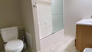 Een badkamer met toilet, douchecabine en wastafel.