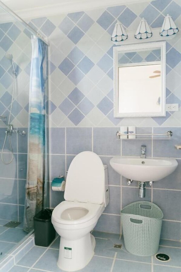 A bathroom with a toilet, sink, shower, and a mirror. - Saipan Emerald Villa (Saipan)