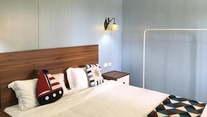 Une chambre d’hôtel avec une tête de lit en bois, un lit recouvert d’une couverture à motifs géométriques, un climatiseur fixé au mur et une table de chevet avec une lampe.