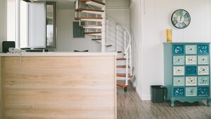Un intérieur moderne avec un comptoir d’accueil en bois, un escalier en colimaçon et un meuble turquoise doté de tiroirs.
