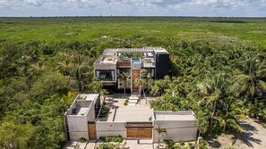 Una casa moderna con piscina, circondata da vegetazione lussureggiante.