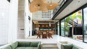 A spacious interior with a modern kitchen, dining area, and seating with large windows and natural light.
