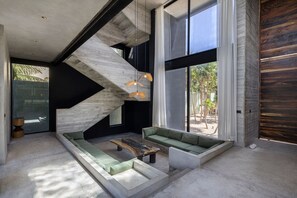 Un interno moderno con una scala in cemento, un divano componibile e ampie finestre.