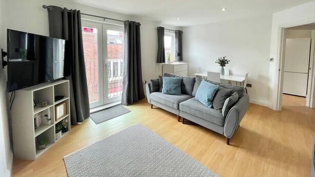 A modern living room with a grey sofa, a flat-screen TV, and a white cabinet. - Modern, fresh & spacious apartment with parking (Bristol)