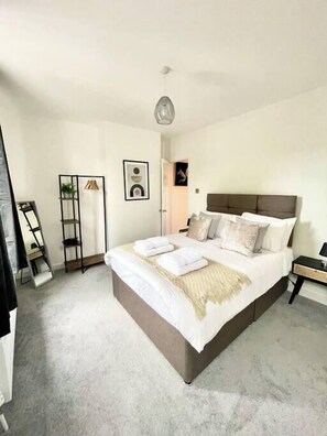 A modern bedroom with a large bed, a bedside table, a wardrobe, and a hanging light fixture. - Gatton House - Sleeps 6 - BS2 (Bristol)