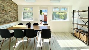 A modern dining room with a wooden table and black chairs, skylights, and a view of greenery outside. - Hereford House – Sleeps 8! BS2 (Bristol)