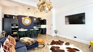 A modern living room with a sofa, ottoman, and a large rug. - The Penthouse BS3 (Bristol)