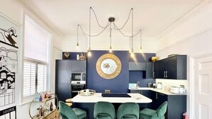 A modern kitchen with a central island, bar stools, and a decorative wall piece. - The Penthouse BS3 (Bristol)