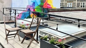 A rooftop terrace with a colorful mural, seating, and potted plants. - The Penthouse BS3 (Bristol)
