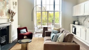 Una sala de estar moderna con chimenea, un sillón rojo, un sofá marrón y una zona de comedor con mesa y sillas.