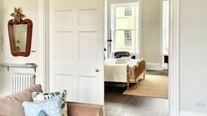 Una habitación con un sofá color beige, un espejo y un radiador.