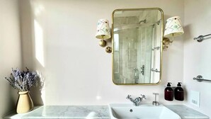 A bathroom with a marble sink, a large mirror, and two wall-mounted lamps. - Pulteney Bridge Suites - Apartment 2A (Bath)