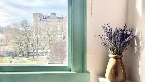 A view through a window with a vase of lavender on a marble ledge. - Pulteney Bridge Suites - Apartment 2A (Bath)