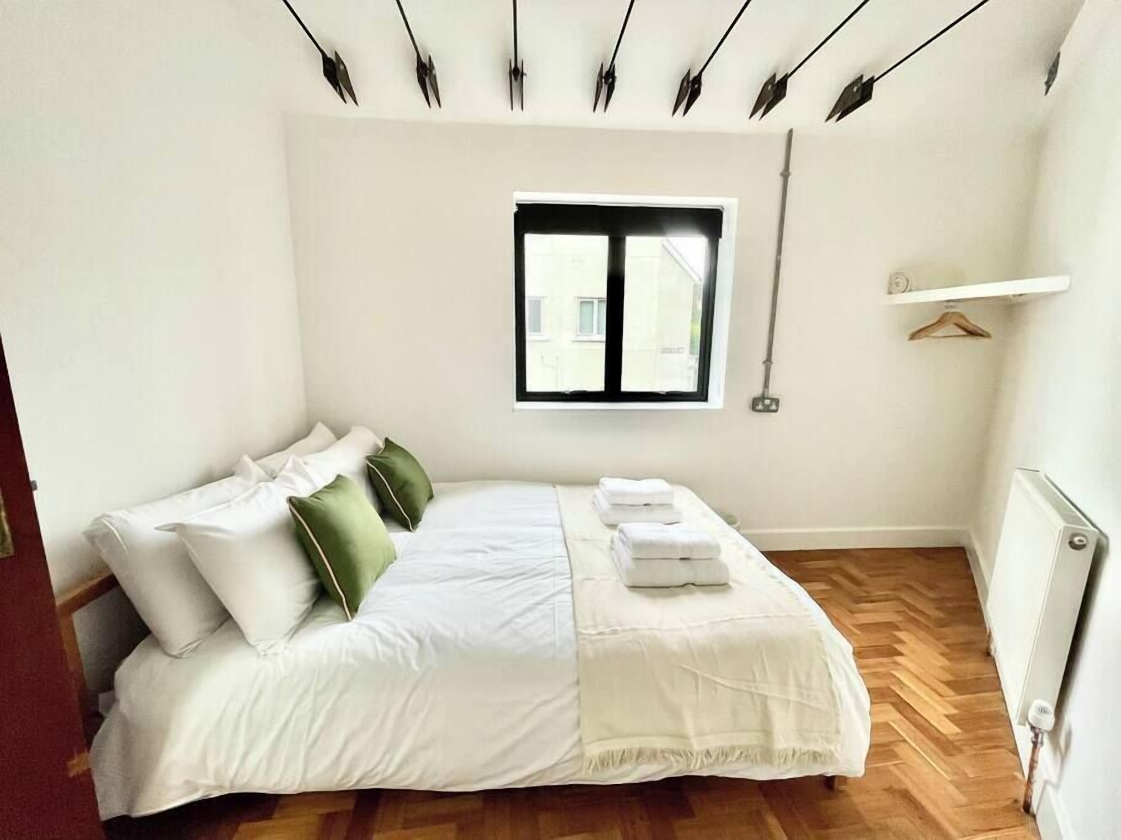A bedroom with a bed, pillows, a window, and a radiator.