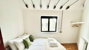 A bedroom with a bed, pillows, a window, and a radiator.