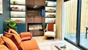Un salon moderne comprenant un canapé, un fauteuil et un meuble de rangement intégré pour les appareils multimédias.