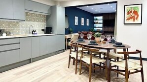Une cuisine moderne avec des meubles gris, un pare-feu en carreaux et un coin repas comprenant une table et des chaises en bois.