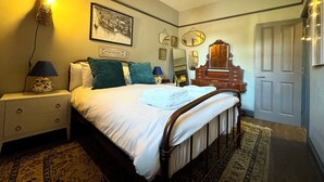A bedroom with a bed, bedside lamps, a dresser, a mirror, and a door.
