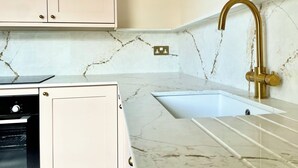 A kitchen with white cabinets, a marble countertop, a gold faucet, and a built-in oven.