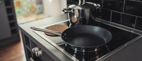 A kitchen with a stove, a frying pan, and a pot.