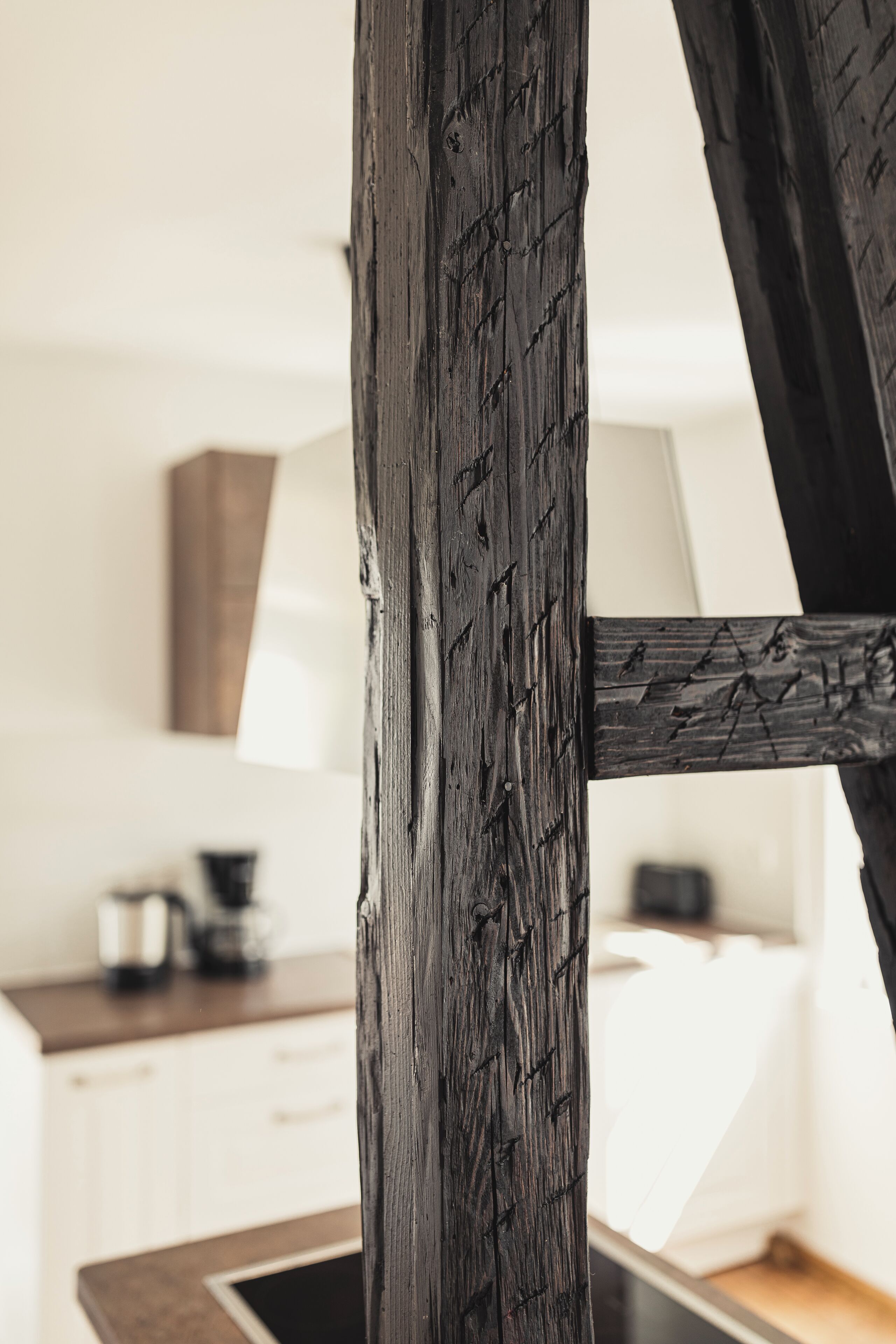 Detailaufnahme eines Holzbalkens mit rustikaler Struktur, Teil der Raumarchitektur.
